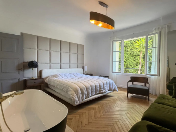 Chambre spacieuse avec lit king-size, baignoire et vue sur le jardin à Cannes.