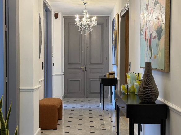 Couloir d'un appartement rénové à Cannes avec un sol en carrelage et des murs clairs.