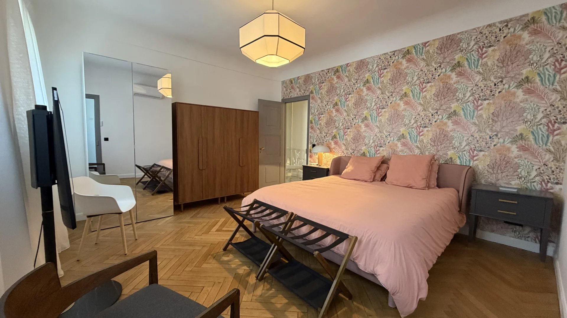 Chambre d’appartement à Cannes Chambre d'appartement rénové à Cannes avec lit, décor floral et mobilier moderne.