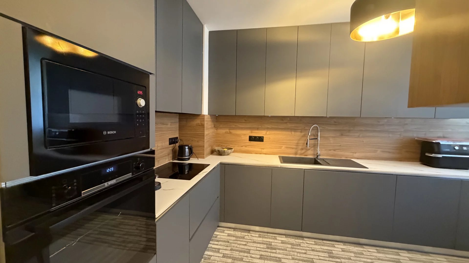 Cuisine d’un appartement à Cannes Cuisine moderne avec des armoires grises et un plan de travail en marbre.