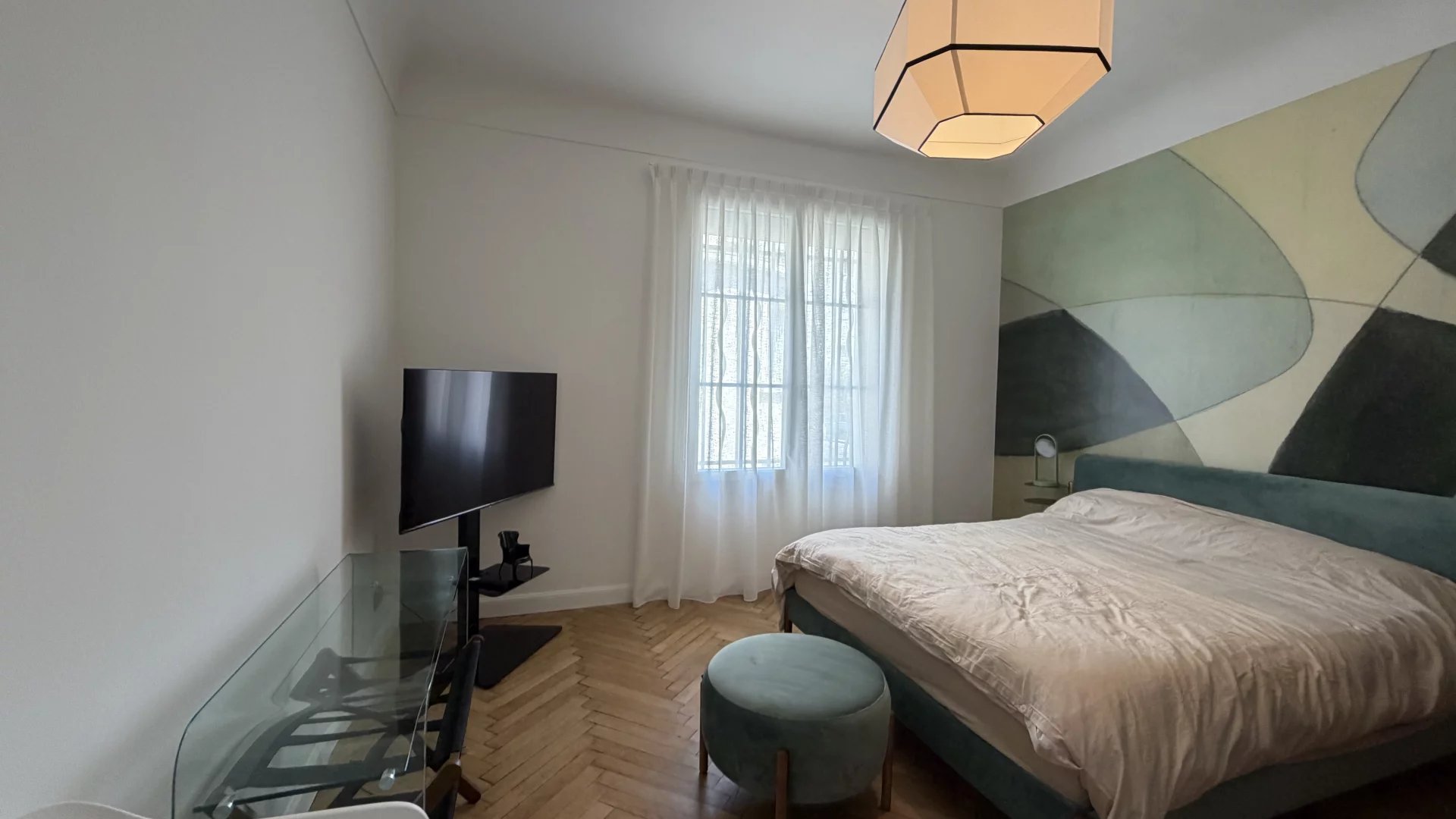 Chambre d’appartement à Cannes Chambre d'un appartement rénové à Cannes, avec un lit, télévision et fenêtres lumineuses.