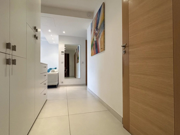 Entrance to a modern apartment with light walls and tiled floor.