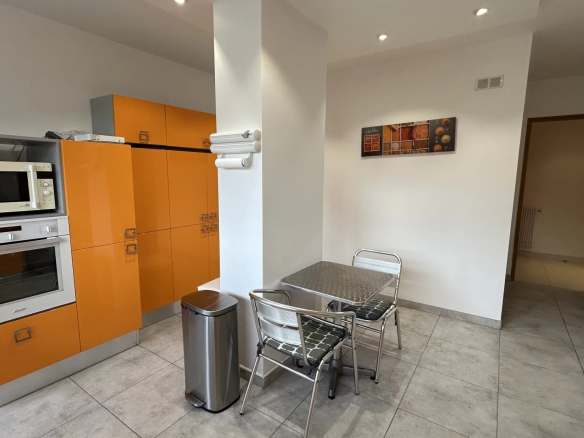Modern kitchen with orange furniture and metal table, apartment in Cannes.