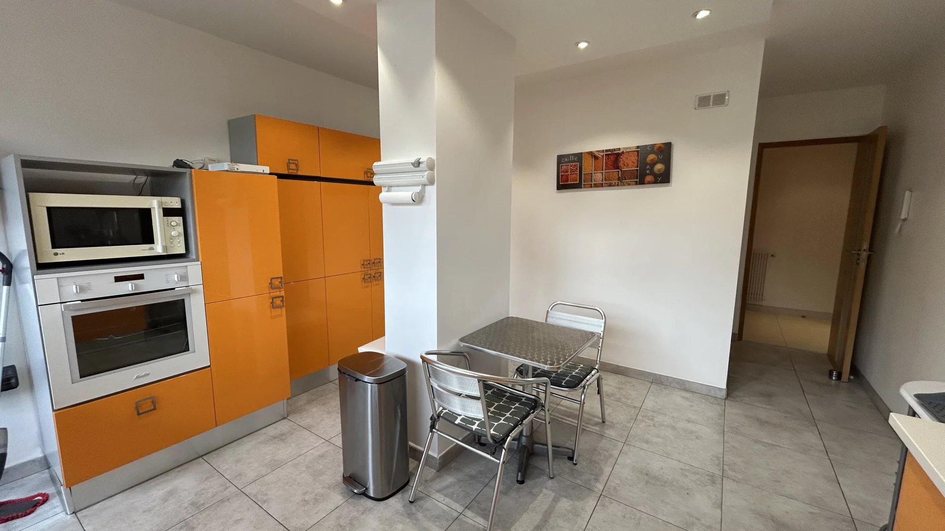 Kitchen of an apartment in Cannes Modern kitchen with orange furniture and metal table, apartment in Cannes.