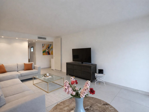 Bright living room of a 76 m² apartment in Cannes, with sofa, television and modern decor.