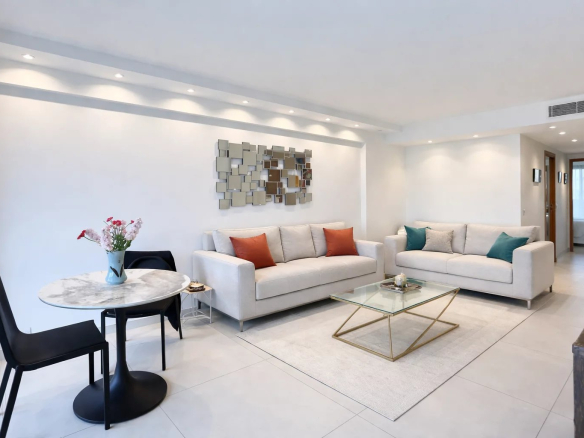 Living room of a modern apartment with light-colored sofas, dining table and contemporary decor.