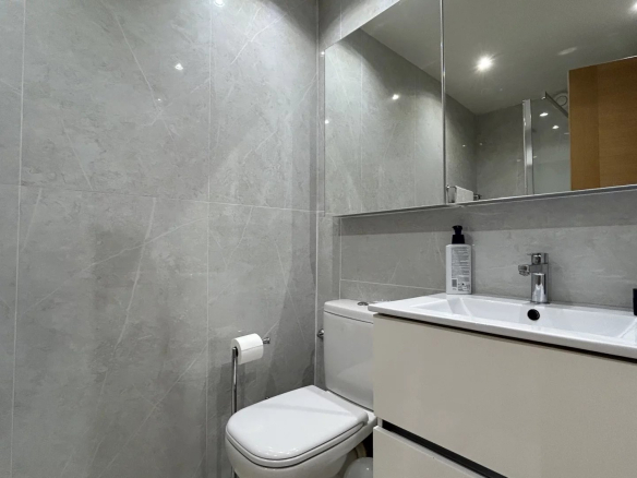 Modern bathroom with grey tiles, sink and mirror.