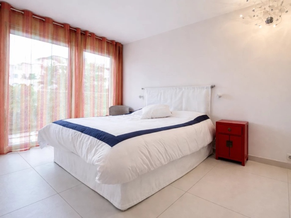 Room in a Cannes apartment with a double bed and windows overlooking the outside.