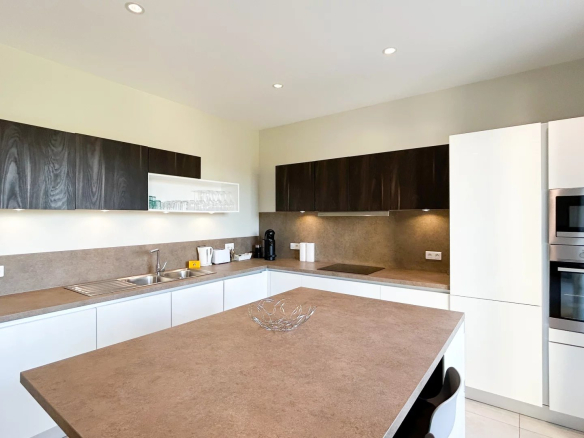 Cuisine moderne d'un appartement à Cannes avec un îlot central et des meubles en bois et blanc.