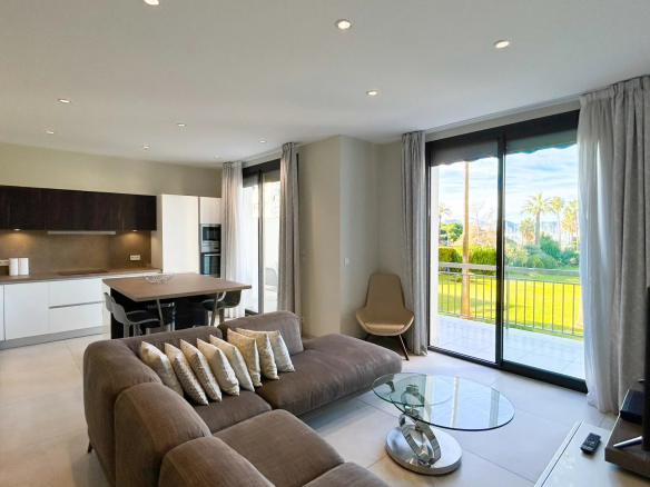 Intérieur d'un appartement moderne avec salon, cuisine ouverte et vue sur un jardin à Cannes.