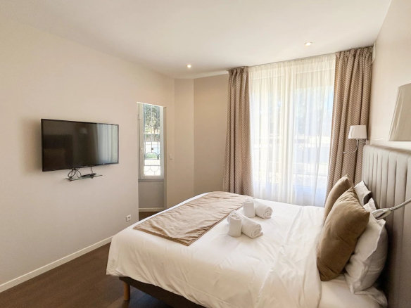 Chambre d'un appartement rénové à Cannes avec lit double et télévision.