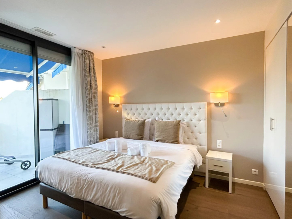 Chambre d'un appartement rénové avec lit double et accès à une terrasse à Cannes.