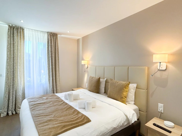 Chambre d'un appartement rénové sur la Croisette à Cannes, avec lit double et décoration élégante.
