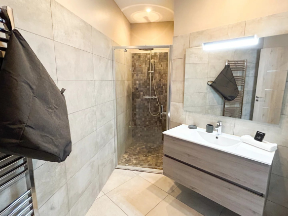 Salle de bain moderne avec douche et meuble vasque, décorée de carrelage gris.