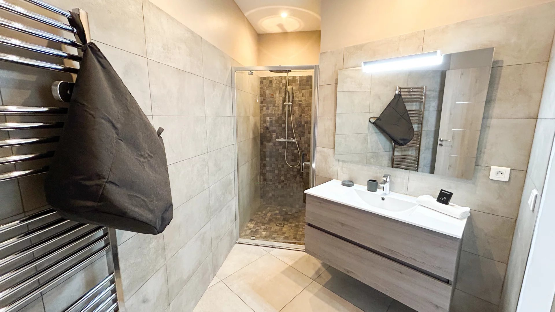 Salle de bain élégante à Cannes Salle de bain moderne avec douche et meuble vasque, décorée de carrelage gris.