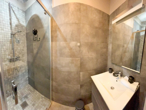 Salle de bain moderne avec douche à l'italienne et lavabo dans un appartement rénové.