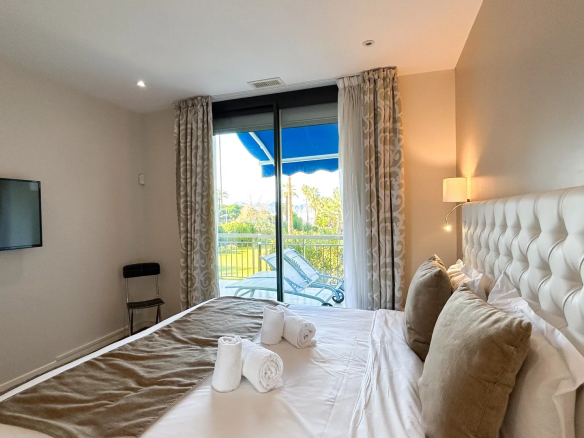 Chambre d'un appartement rénové avec lit double et vue sur balcon à Cannes.