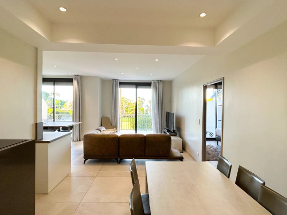 Intérieur d'un appartement moderne avec salon et salle à manger, lumière naturelle, vue sur la Méditerranée.