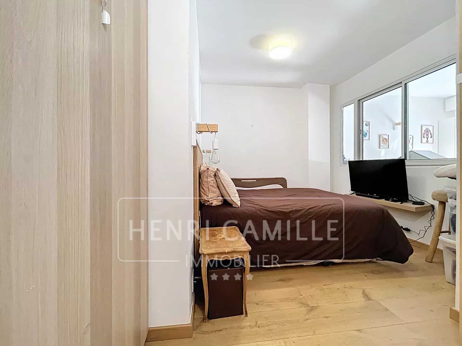 Chambre d'un appartement à Le Cannet avec lit, télévision et parquet.