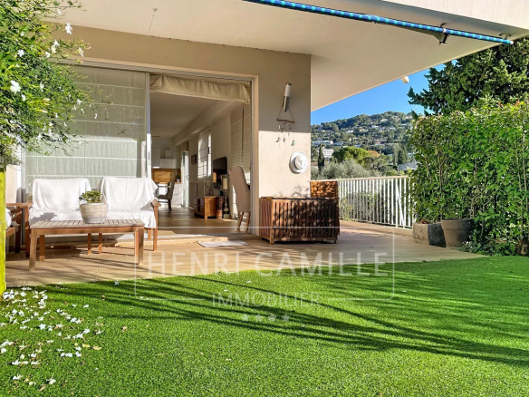 Terrasse d'un appartement avec jardin, mobilier en bois et vue dégagée sur la nature.