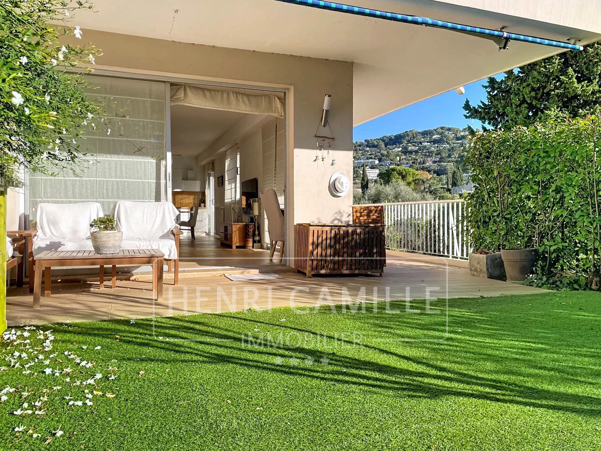 Terrasse d'un appartement avec jardin, mobilier en bois et vue dégagée sur la nature.