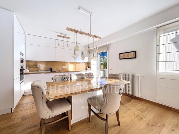 Cuisine moderne avec table à manger en bois et chaises dans un appartement lumineux.