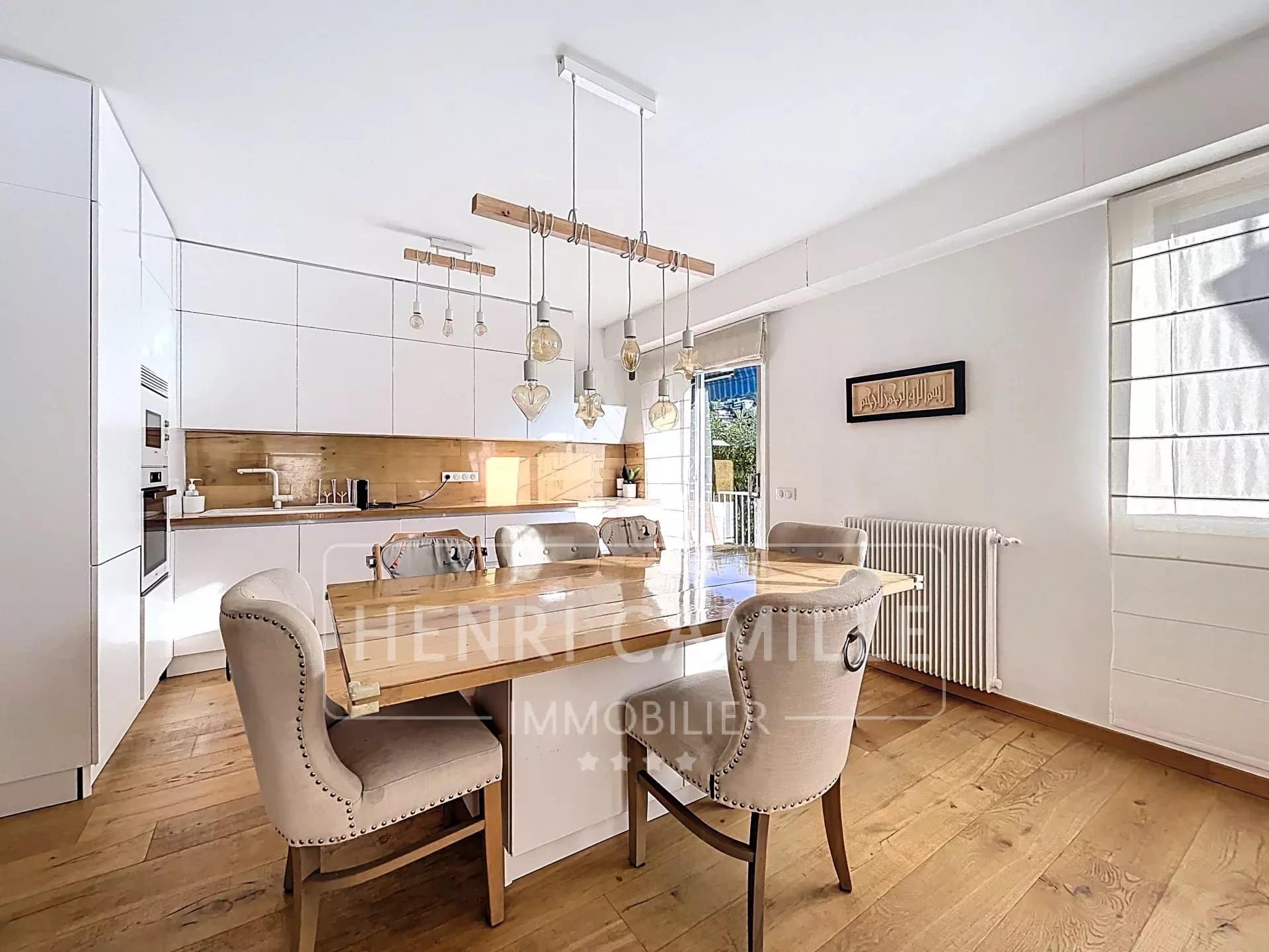 Cuisine moderne avec table à manger en bois et chaises dans un appartement lumineux.