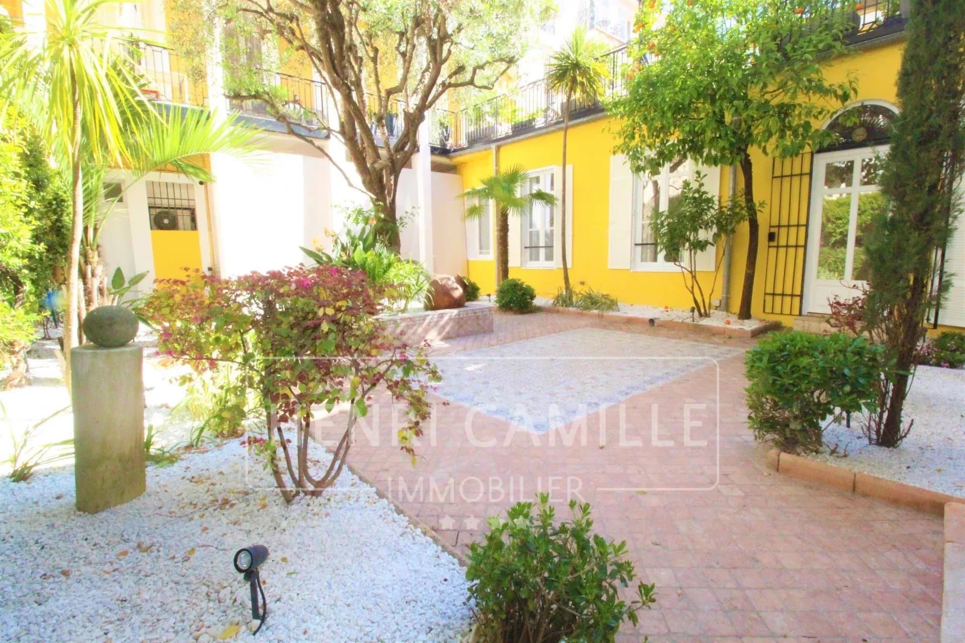 Terrasse/jardin calme d'un appartement à Cannes, avec plantes et pavés.