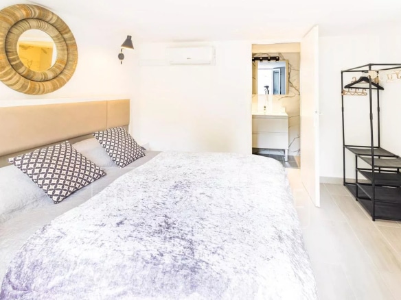 Chambre d'une villa contemporaine avec lit double et salle de bain attenante.