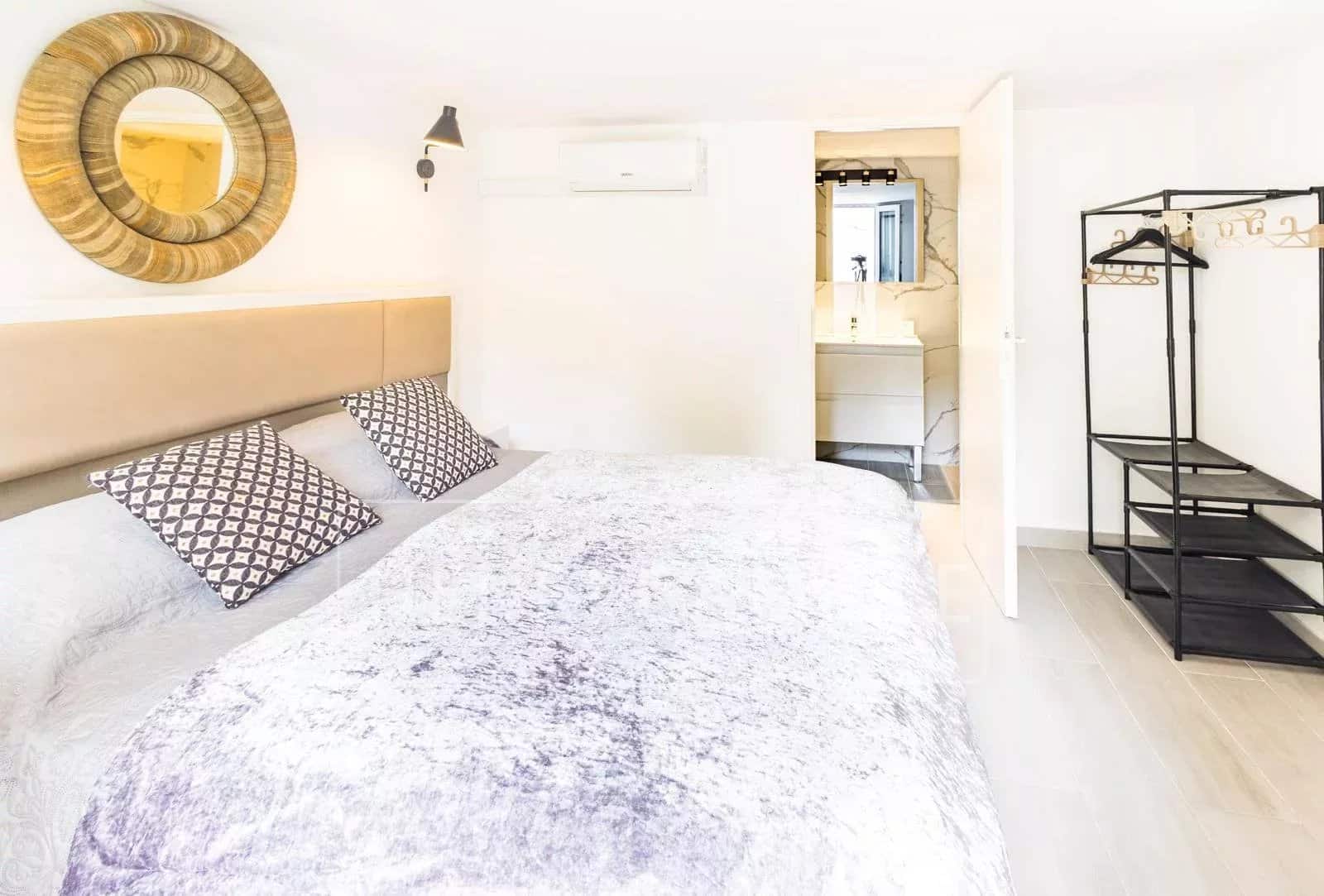 Chambre d'une villa contemporaine avec lit double et salle de bain attenante.
