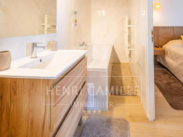 Salle de bain moderne avec baignoire et meuble en bois.