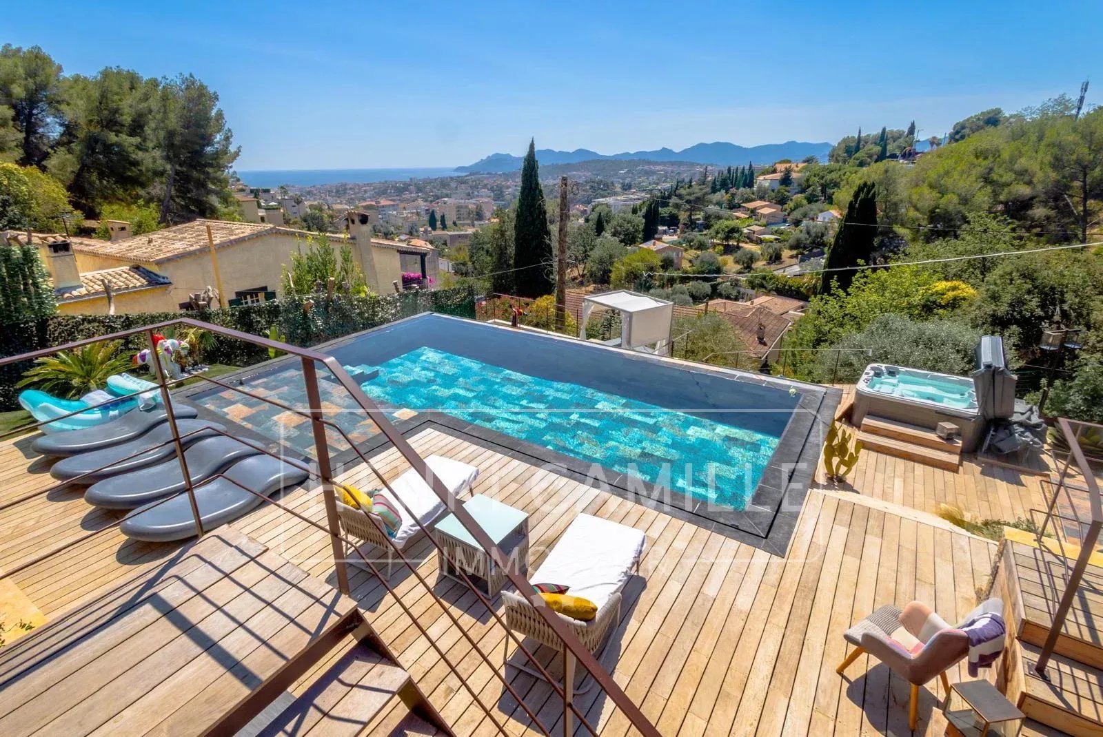 Vue de la piscine et de la terrasse d'une villa contemporaine au Cannet, avec vue sur la mer et les collines.