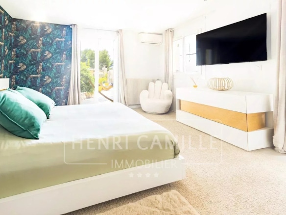 Chambre moderne avec lit double, décoration contemporaine et télévision, vue sur jardin.