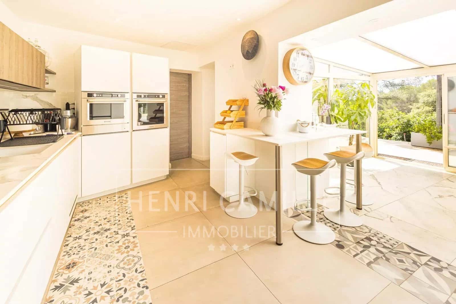 Cuisine moderne et lumineuse d'une villa contemporaine avec bar et accès à un jardin.