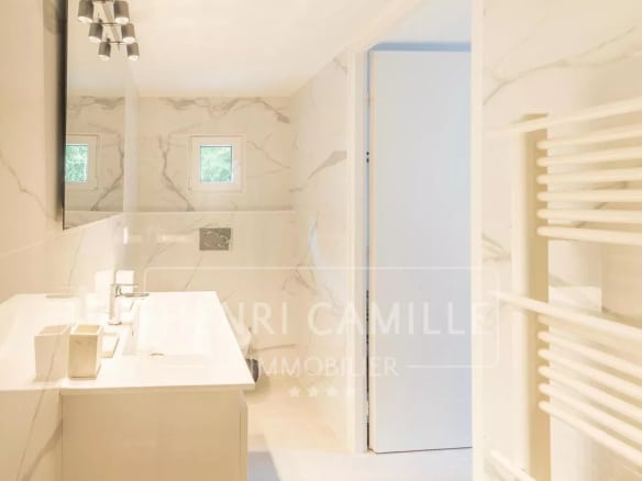 Salle de bain moderne avec carrelage en marbre et lavabo double.