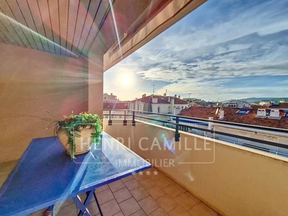 Terrasse d'un appartement en duplex avec vue sur Cannes, ciel dégagé et soleil couchant.