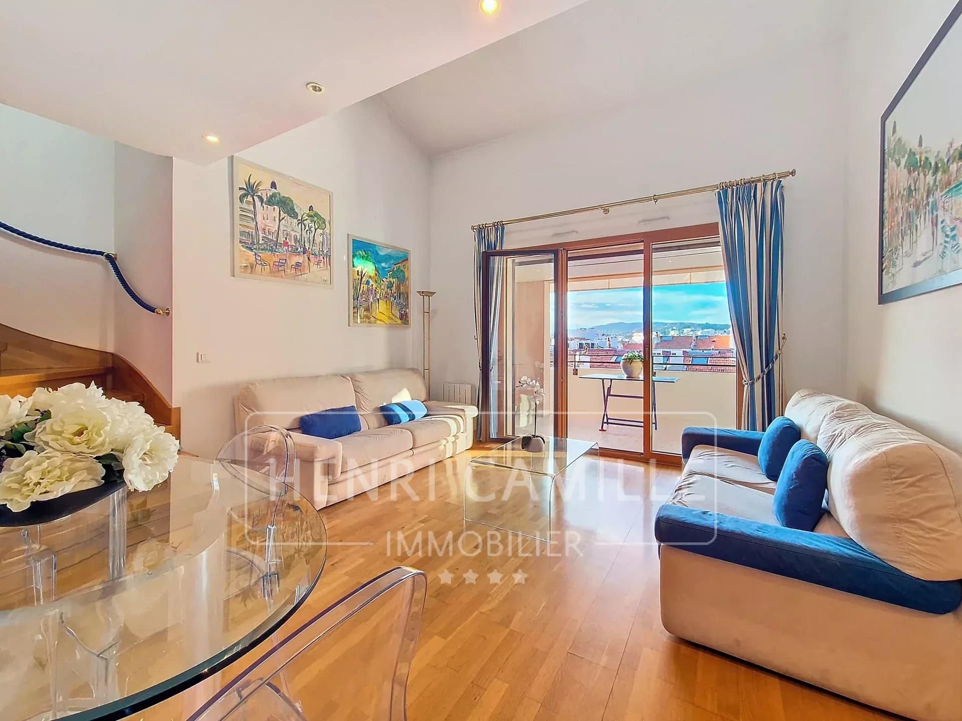 Séjour lumineux avec canapé et accès à une terrasse, vue sur Cannes.