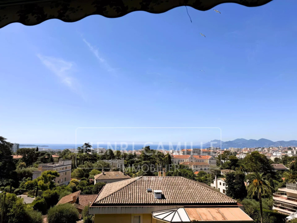 Panoramic sea view from a residence in Cannes, with houses and trees in the foreground.