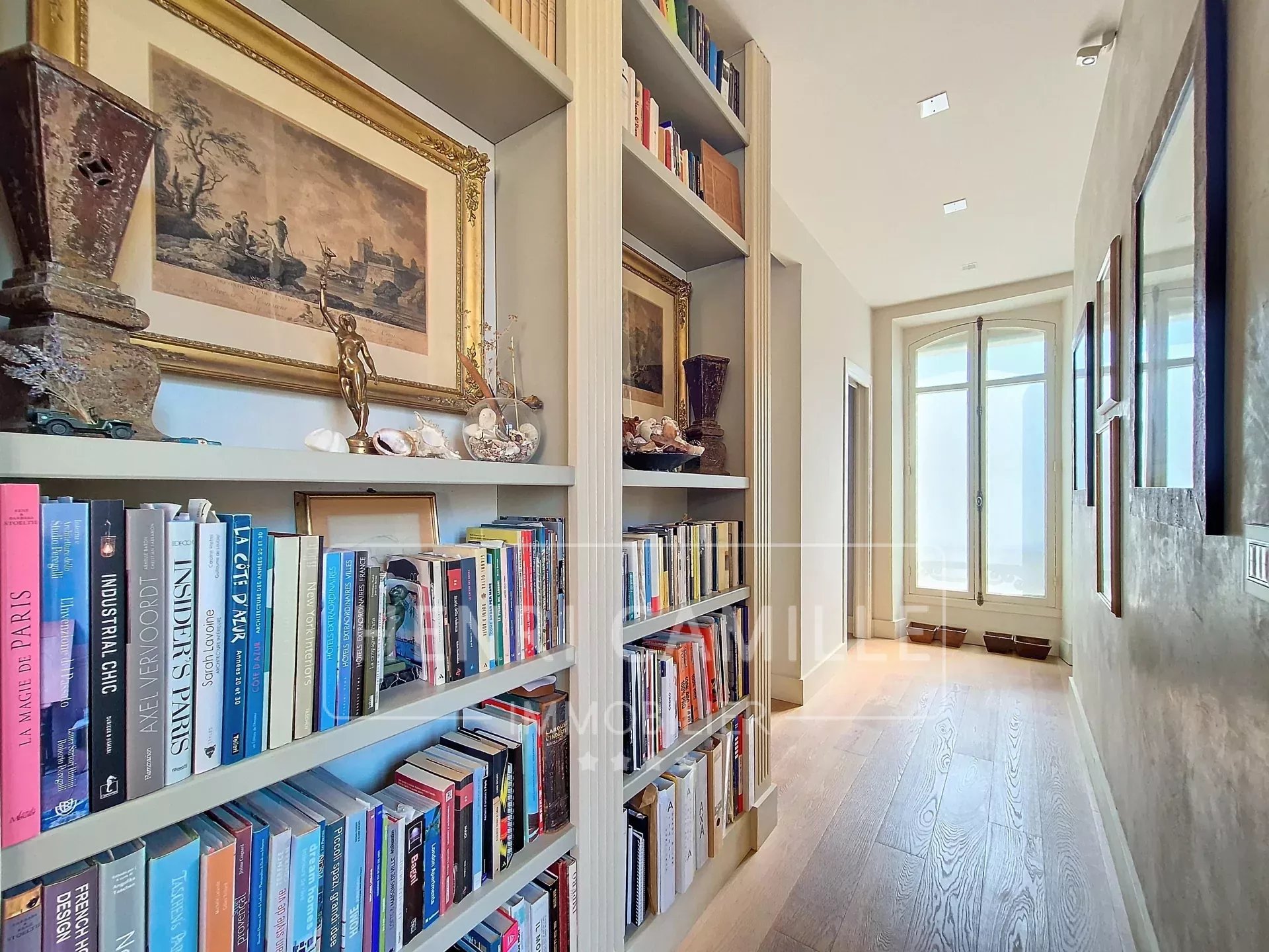 Hallway of a renovated apartment with shelves filled with books and artwork.