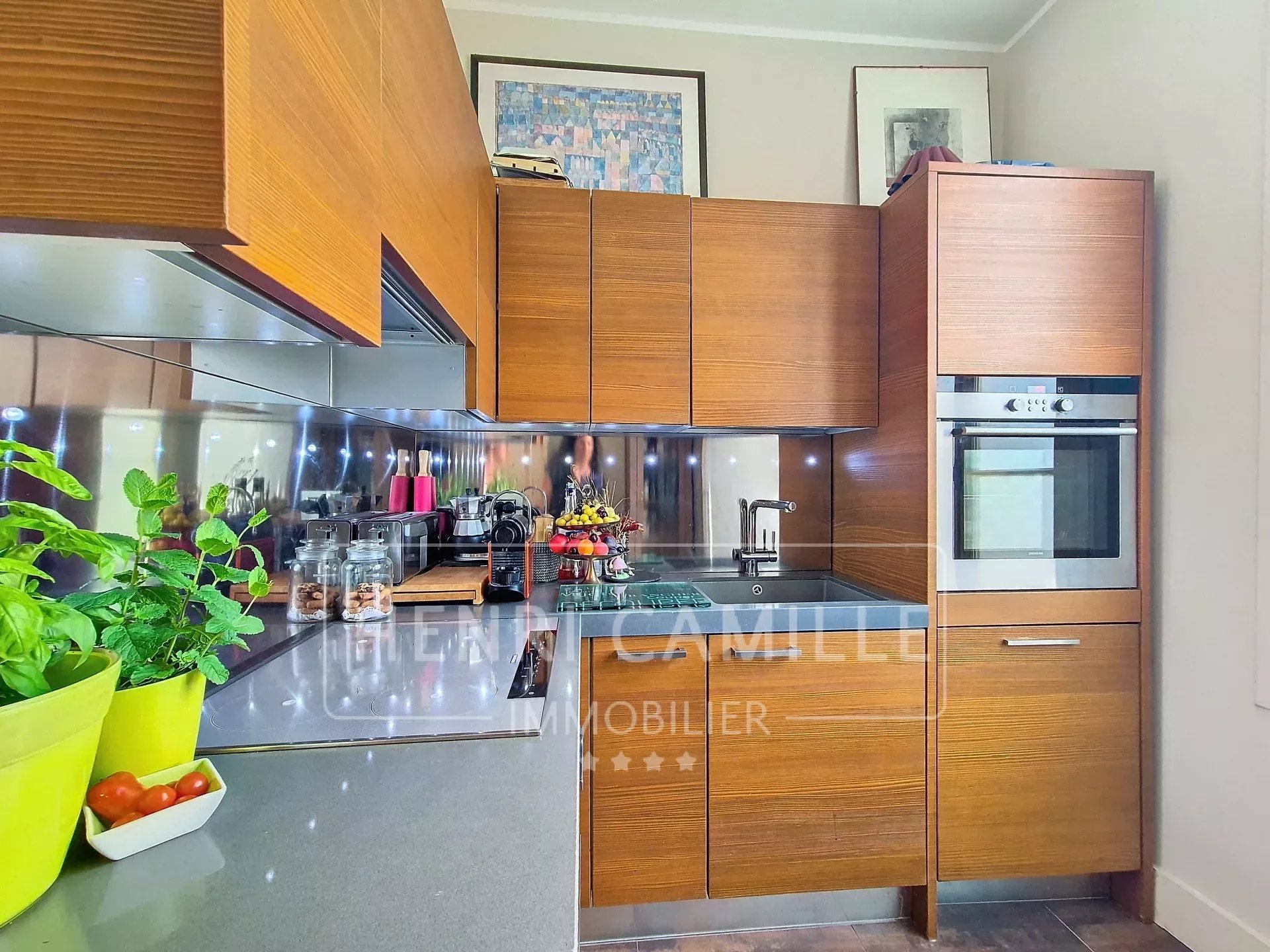 Modern kitchen with wooden furniture and granite worktop in an apartment in Cannes.
