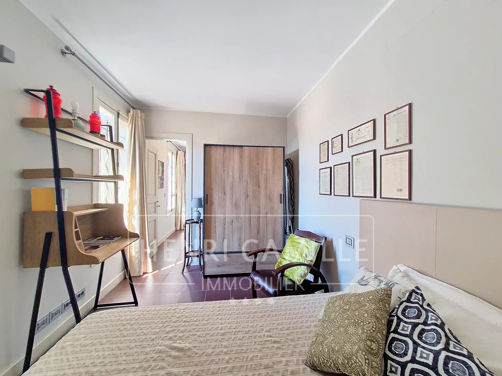 Bedroom in a Cannes apartment with modern decor and desk.
