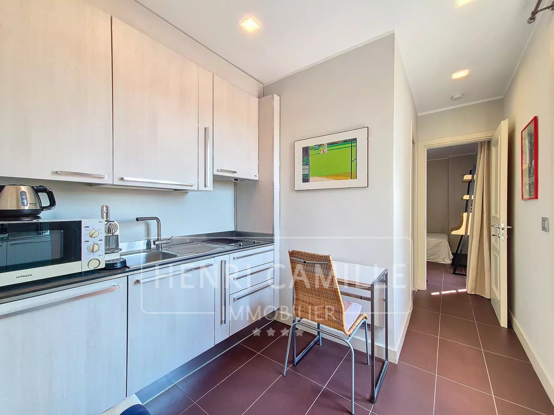 Modern kitchen in a Cannes apartment with light-colored furniture and appliances.