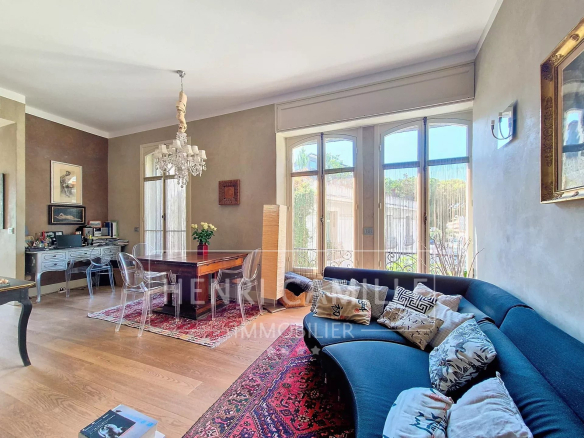 Bright living room of an apartment in Cannes with a large sofa and a dining table.