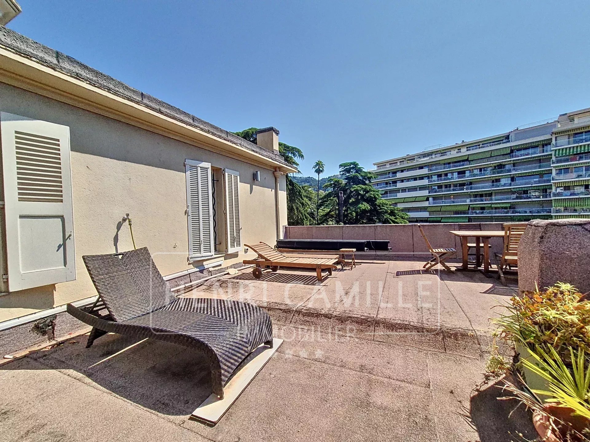 Spacious terrace of an apartment in Cannes, with sun loungers and garden furniture.