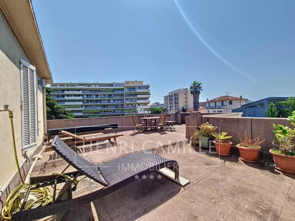 Spacious terrace with sun loungers and plants, overlooking buildings in Cannes.