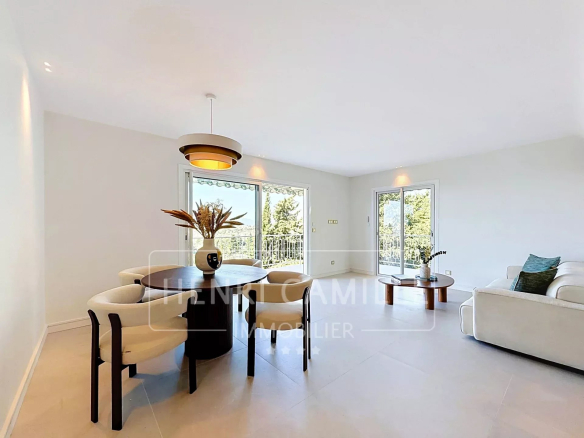 Intérieur d'un appartement rénové à Cannes avec salon, salle à manger et accès à une terrasse.