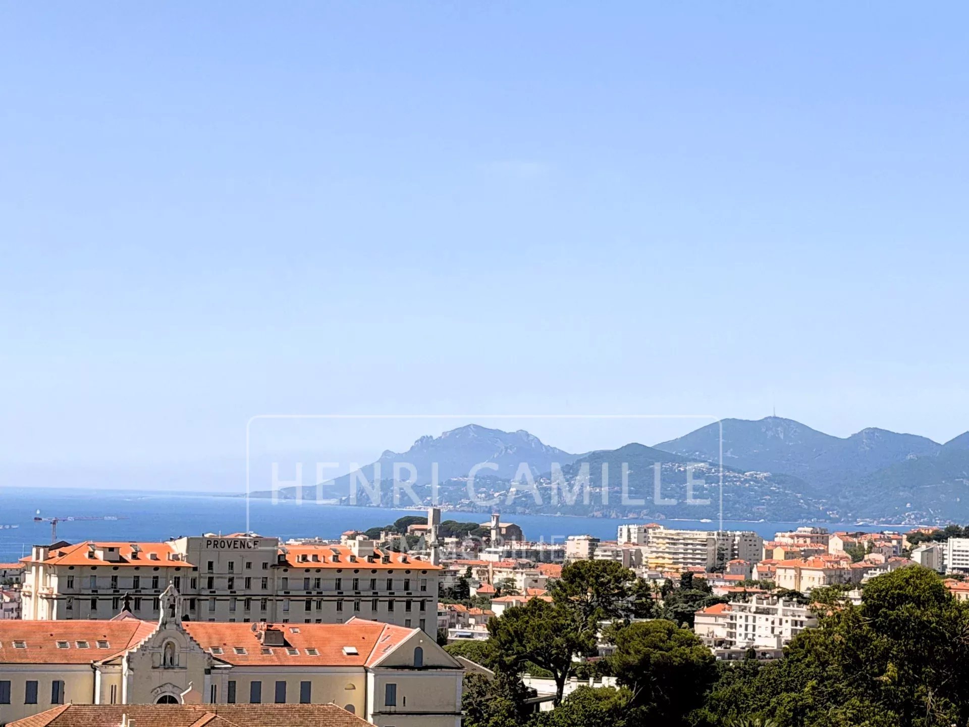 Vue panoramique sur la mer à Cannes Vue panoramique sur la mer et les montagnes depuis Cannes, avec des bâtiments en premier plan.
