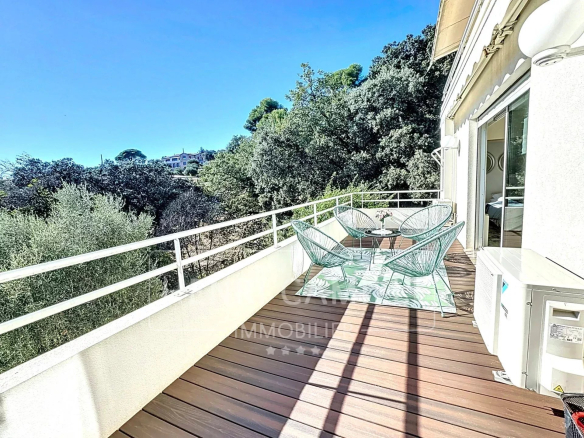 Terrasse en bois avec chaises, vue dégagée sur la mer, entourée de verdure à Le Cannet.