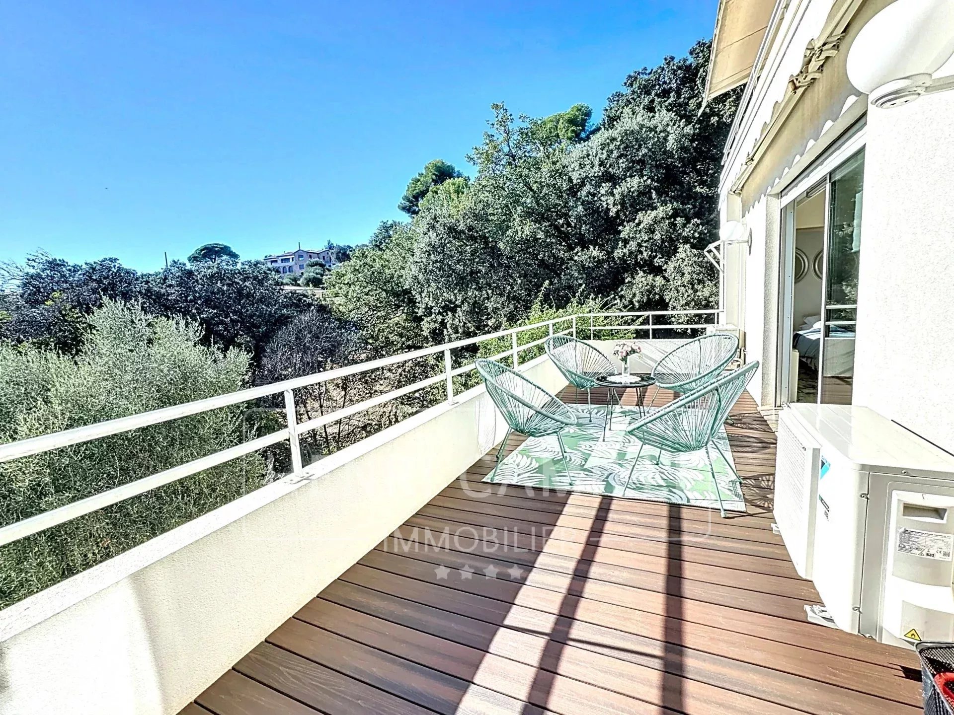 Terrasse avec vue mer à Le Cannet Terrasse en bois avec chaises, vue dégagée sur la mer, entourée de verdure à Le Cannet.