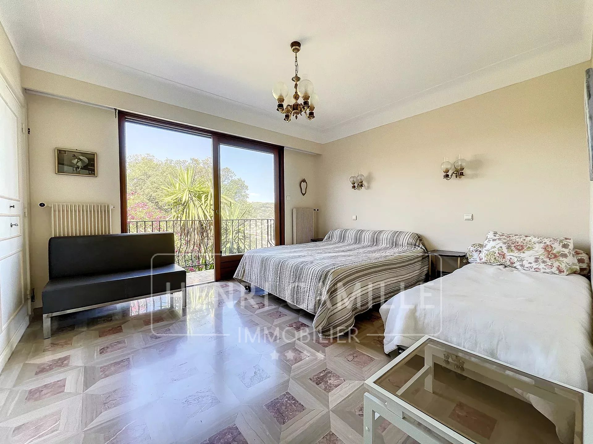 Chambre spacieuse avec fenêtres donnant sur un jardin à Cannes, mobilier simple.